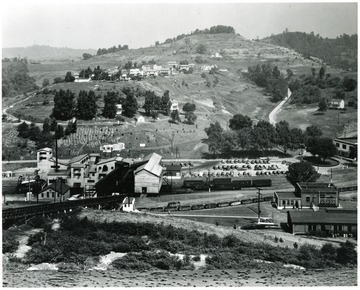 A processing plant sits below miner's homes and open countryside.