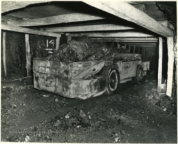 A miner moves a fully loaded shuttle car down the mine shaft.