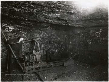 Two miners operate the breast type coal cutting machine.