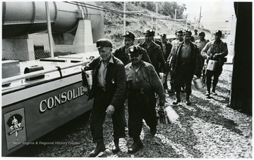 Miners leaving roofed man trip car at shifts end.