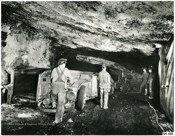 Men at work with loading machine and shuttle car. Probably Joy Machinery.