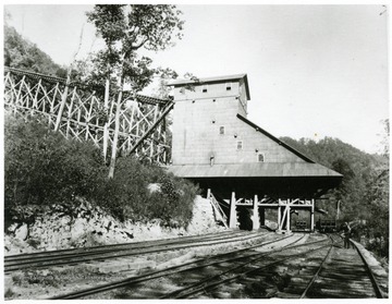 Man standing on tracks next to tipple.