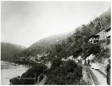 Men and women standing on the railroad tracks outside of a New River Coal mine camp.