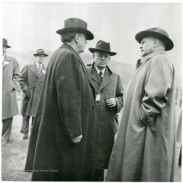 Three coal officials talking outside.