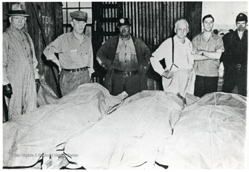 Miners and others stand over the covered bodies of miners killed at Downaton Point, Ohio.