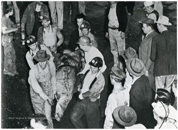 Miners carry the body of a miner past onlookers.