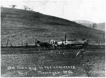 Two men drive a horse drawn cart carrying wooden caskets to the Monongah Cemetery.