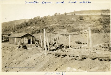 Mine No. 36 motor barn with broken mine cars outside of it. 