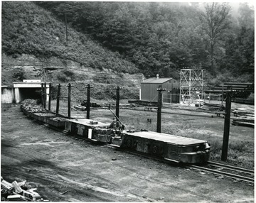 A miner operates a cart full of coal exiting the mine.  