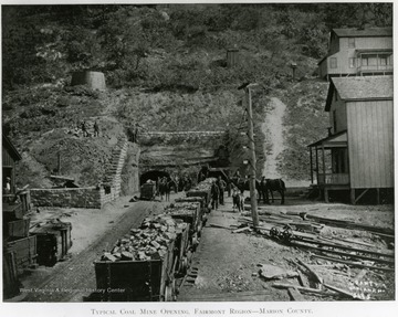 Coal mine opening around the Fairmont region in Marion county. Line of filled coal cars with men and horses standing next to them. 