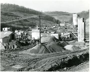 Miners working with machinery near coal preparation plant. There is a church visible in the background.