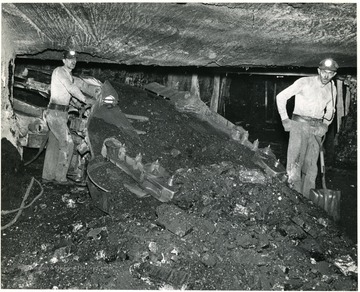 Two miners operating a loading machine.