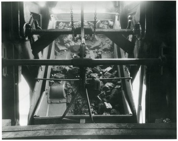 'Coal at all White Oak shafts mines is handled on self dumping cages, which handle the coal uniformly and with a minimum of breakage. Note how evenly the coal is flowing from the mine car. Much more rapid of course than the picture indicates, but it shows how well designed the equipment must be to handle the coal in such splendid manner.'