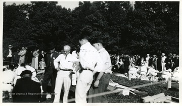 Men watch as teams participate in safety and rescue training exercises.