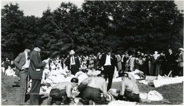 Group of men rehearsing mine safety procedures as crowds watch. 