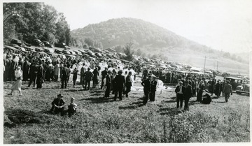 Group of men rehearsing mine safety procedures as crowds watch near parking area.