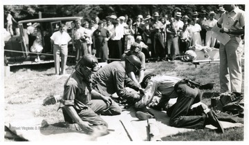 Group of men rehearsing mine safety procedures on a practice victim. 