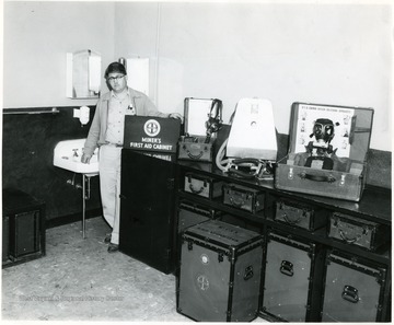 Man standing in first aid room with various equipment on top of table.