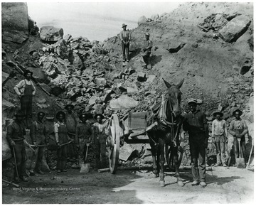 African-American Miners with shovels standing next to horse with cart attached.