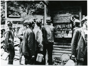 Miners looking at sign telling them there is no work tomorrow.