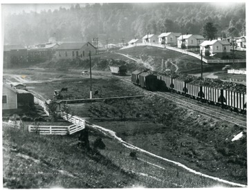 'The one grade White Oak is mighty proud of, is its Domestic Mine Run. Here yousee twenty-two cars of this grade at our Cranberry No. 3 Mine. This Mine Run is very coarse; free from impurities; has a bright shiny appearance and we ship a million tons of it every year. Just think of it, 20,000 cars of this fine fuel shipped to satisfied customers each year. We also want you to notice the background of the picture, showing the neat homes occupied by the men who mine White Oak coal. Notice also how neat the surroundings are. Houses are kept neatly painted; yards fensed; grounds kept clean and everything possible done to provide a nice place for employees to live.' 