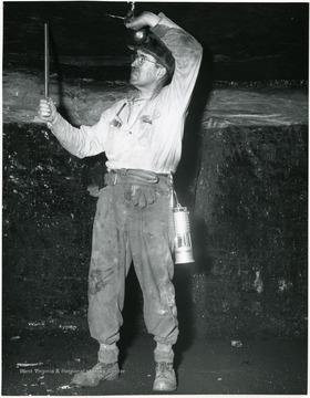 Miner putting bolts into the roof of a mine for support.