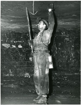 Miner putting bolts into the roof of a mine for support.