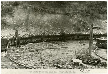 Men lean against coal cars at the Tram Road of Winifrede Coal Co., Winifrede, W. Va.