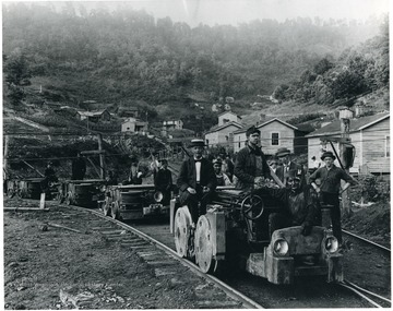 Miners riding tram engines with company houses in the background; United Poca Coal Co., Crumpler, W. Va.