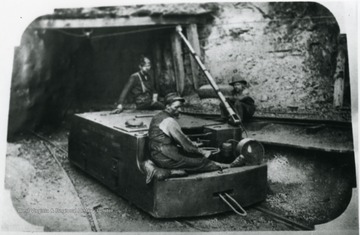 Miners on an electric locomotive used in hauling mine cars.