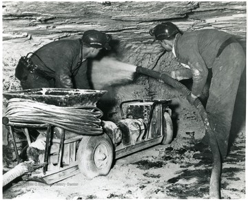 Two miners dust the side walls of Mine No. 207 for safety. 