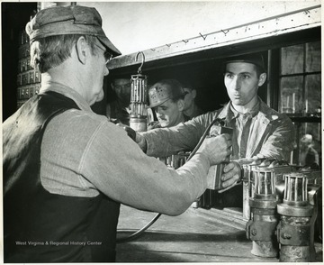 'Shinnston, West Virginia (Jan. 1945, Joe Akers, 32 year old bituminous coal miner and 400,000 fellow miners in America's bituminous coal industry are the worlds most prosperous coal miners.' Picture shows: Joe gets his mine lamp. Its 2:45 and in 15 minutes Joe will be riding into the mine to start the day's work. These lamps, electrically operated, are turned back to the lamphouse at the end of each working day, when they are recharged by the lamphouse man. From Hamilton Wright Org. For Bituminous Coal Industry. Photo Gratis.'