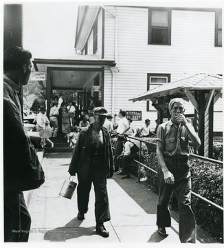 Coal miner walks with his son outside of store.