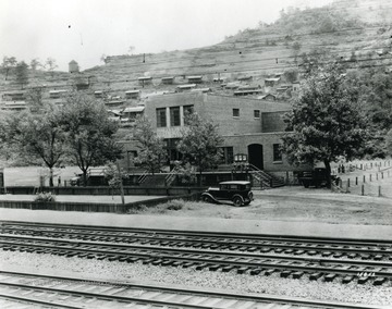 Building of the Peerless Coal and Coke Co. with a few cars and people outside.