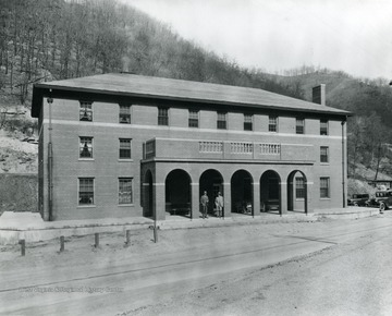 Two men stand in the archways at the entrance to the company store and office.