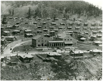 Coal town with Company building in the center. Sign on front of building says 'Safety The First Consideration.'