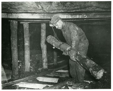 Miner carrying a large piece of wood.