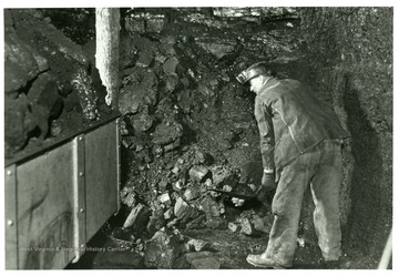 A miner shovels coal into a car for removal from the mine.