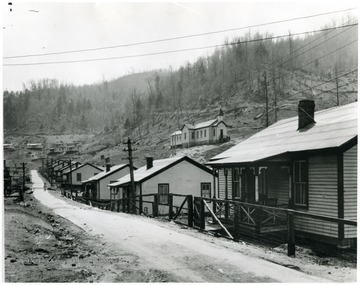 Row of houses along a road with somebody walking in the distance.