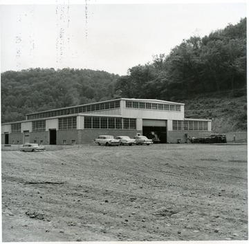 Large building with cars and a few people outside.