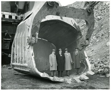 Group portrait of men standing in a shovel scoop.