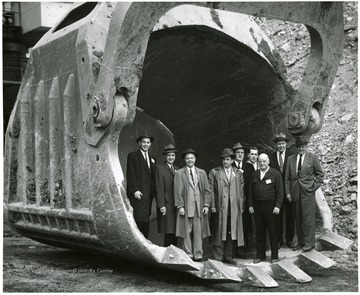 Tour group standing in scoop of giant shovel.