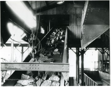 'All sizes of 'White Oak' prepared coal are loaded into railroad cars with loading booms to minimize breakage and preserve the best appearance of the coal. It would be useless to carefully mine and screen our coal if we did not use proper care in loading it into the railroad cars. These booms lower to the bottom of the car when it is first placed under the tipple for loading, and raised from time to time as the car fills up. Note how perfectly screened this lump coal appears on the boom! Not a sign of slack to be seen. Treated for dust if desired.'