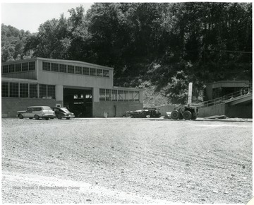 Cars and machinery are parked outside mine plant buildings.