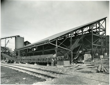 'A sheltered conveyor brings the Disco product from the carbonizers to this sheltered mechanical cooling wharf. A method of careful cooling in motion prevents spontaneous firing of the fuel and avoids injury to the structure of the product. The wharf is contructed of a series of grates, which are successively raised and lowered in a wavelike manner to keep the Disco product in motion and convey it slowly, while it is being cooled, down to the discharge end of the wharf.