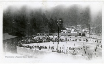 People playing baseball with a crowd surrounding the field watching.