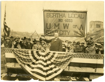 'Taken at W. V. U. Stadium, V. Bittner under speaker's hand, speaker unidentifiable.'