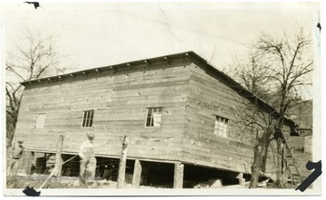 Man leaning on a wire fence beside a wooden building in Wendel, W. Va.