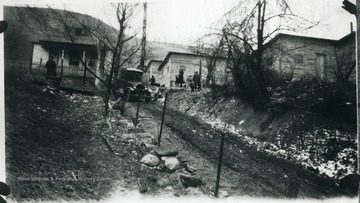 Car on road between a house and barracks.