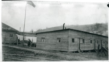 American flag on pole near barracks in Baxter, W. Va. and laundry hanging on line.